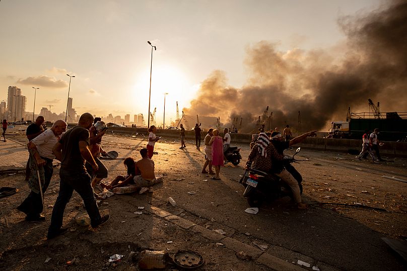 Wounded people are evacuated as smoke rises from a massive explosion in Beirut, 4 August, 2020