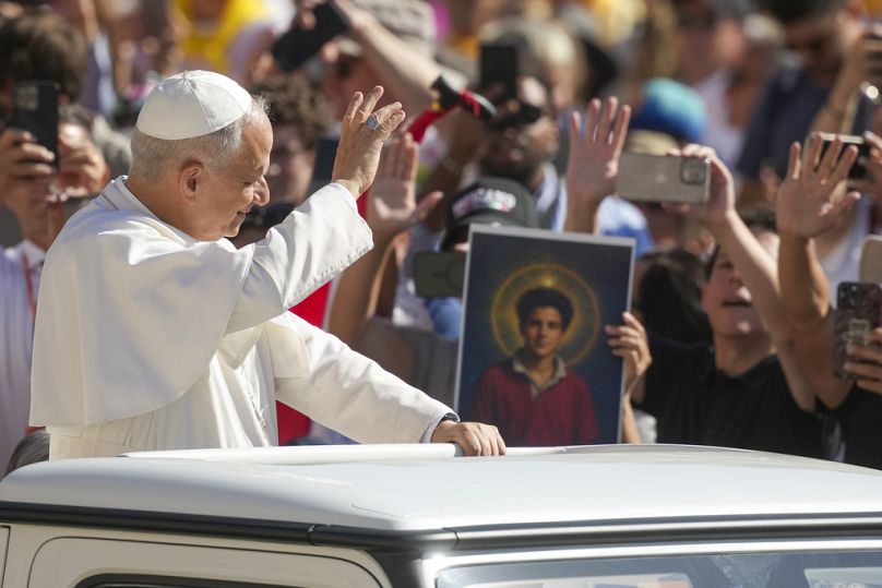 FILE: Pope Leo XIV waves to faithful holding a picture of Carlo Acutis, as he arrives in St. Peter's Square at the Vatican, Sept. 6, 2025
