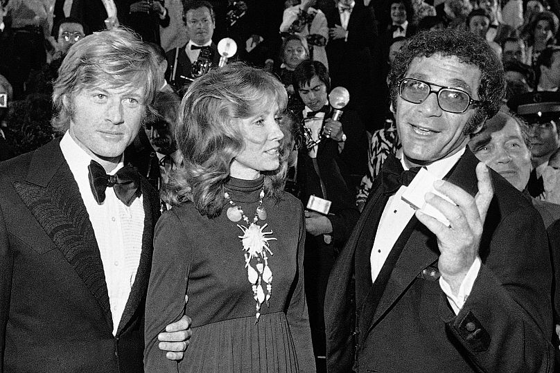 ARCHIVO - Robert Redford, de izquierda a derecha, su esposa Lola y el director Sydney Pollack aparecen en el Festival de Cine de Cannes, Francia, el 7 de mayo de 1972