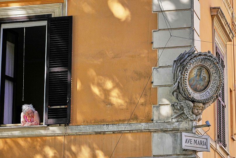 A woman looks out the window to cool off in Rome on 5 August, 2025.