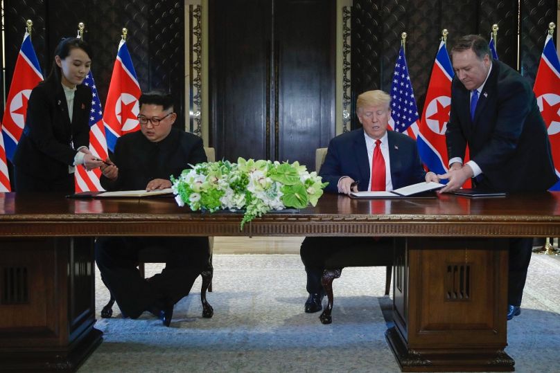 Kim Jodzsong átnyújtja a tollat bátyjának, Kim Dzsongunnak a Donald Trumppal folytatott tárgyalások során Szingapúrban, 2018 júniusában