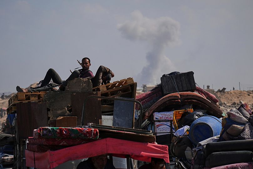 Smoke rises in the background following Israeli bombardment as displaced Palestinians flee northern Gaza, 16 September, 2025