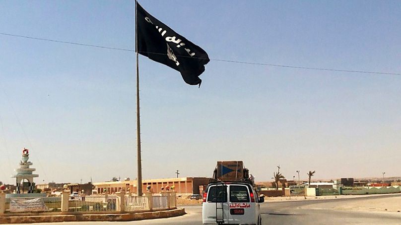 FILE: FILE - A motorist passes by a flag of the Islamic State group in central Rawah, 175 miles (281 kilometers) northwest of Baghdad, Iraq, on July 22, 2014.