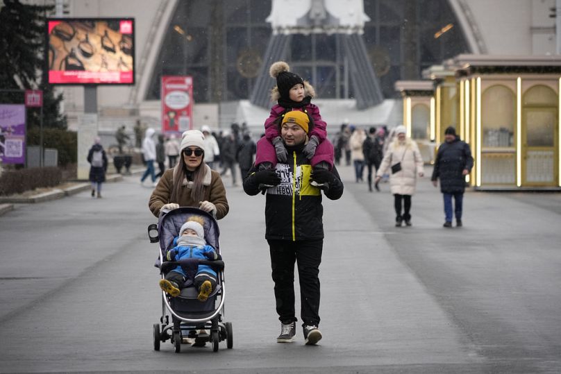 Un couple avec leurs enfants se promène dans une zone sans neige et froide à VDNKh, l'Exposition des réalisations de l'économie nationale à Moscou, en Russie, le 13.02.25