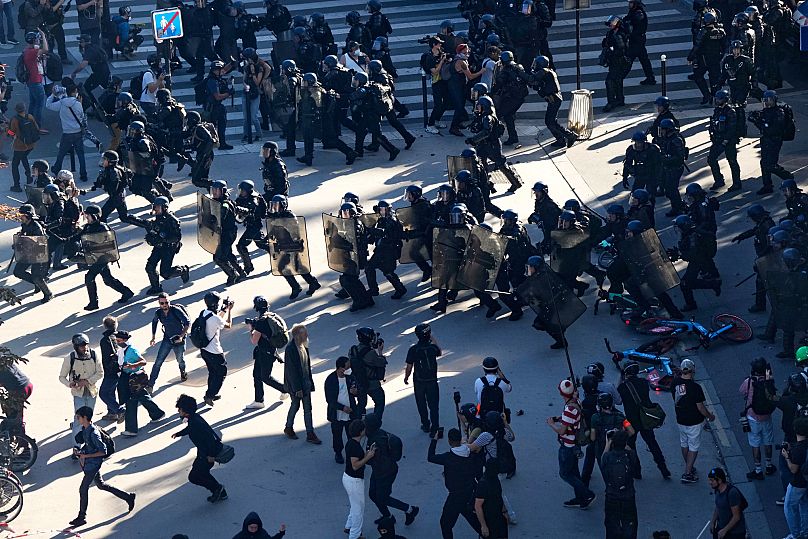 Police officers run toward protesters during a demonstration called by major trade unions to oppose budget cuts in Paris, 18 September, 2025