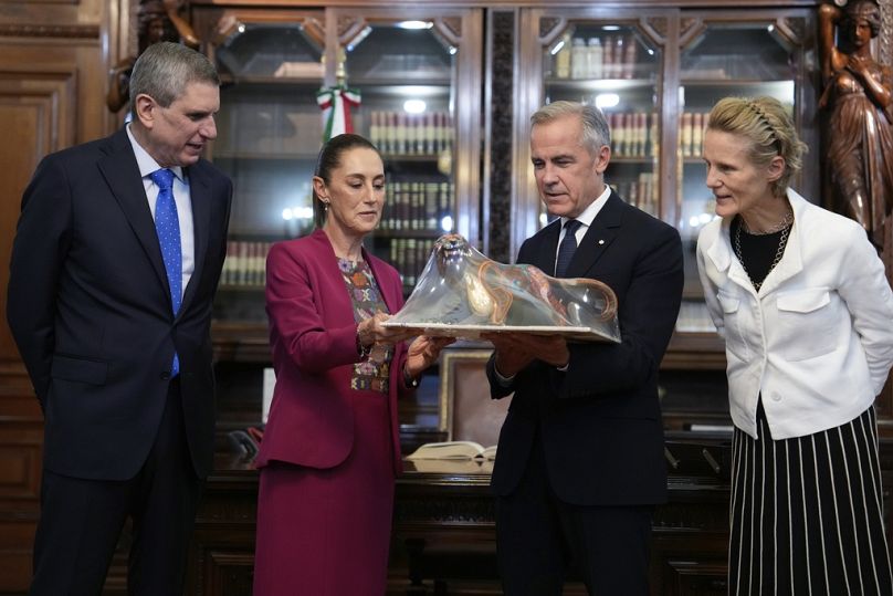 Jesus Maria Tarriba, left, and Diana Fox Carney, right, look on as Mexican President Claudia Sheinbaum presents a gift to Canada's Prime Minister Mark Carney at the National P