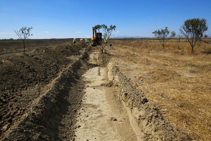 In this Wednesday, May 31, 2017 photo, a bulldozer and workers of Cyprus Missing Persons of the two communities work together during an excavation in a field for missing perso