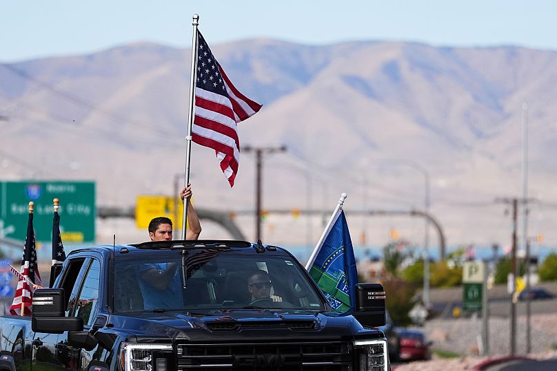 FILE: A person holds a US flag out of a truck's sunroof in tribute to harlie Kirk at Utah Valley University, in Orem, 13 September 2025