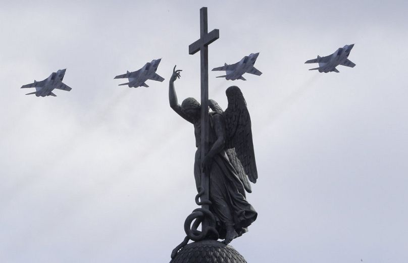 Des avions de chasse supersoniques tout temps à longue portée Mikoyan MIG-31 survolent une statue d'un ange lors du défilé militaire du Jour de la Victoire à Saint-Pétersbourg