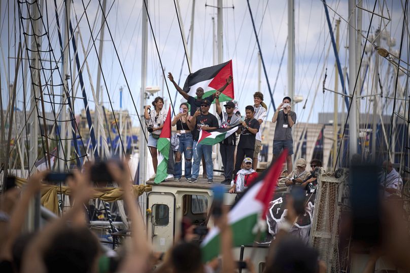 نشطاء يلوّحون من قارب يشارك في أسطول مدني متجه إلى غزة، في برشلونة، 31 أغسطس 2025