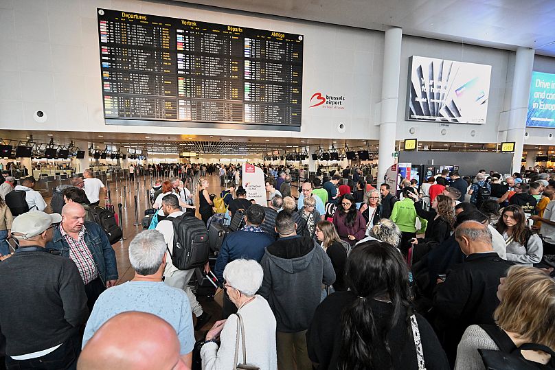 People stand in front of a departure board after a cyber attack caused delays at Brussels International Airport in Zaventem, 20 September, 2025
