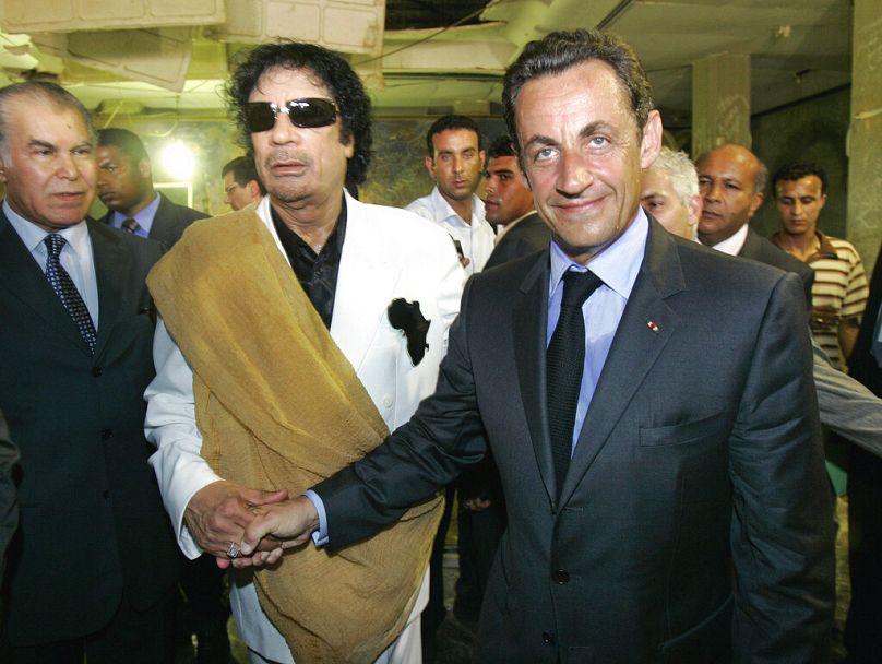 FILE - July 2007 - Libyan leader Moammar Gaddafi, left, shakes hands with French President Nicolas Sarkozy as they visit a house bombed by American airplanes 
