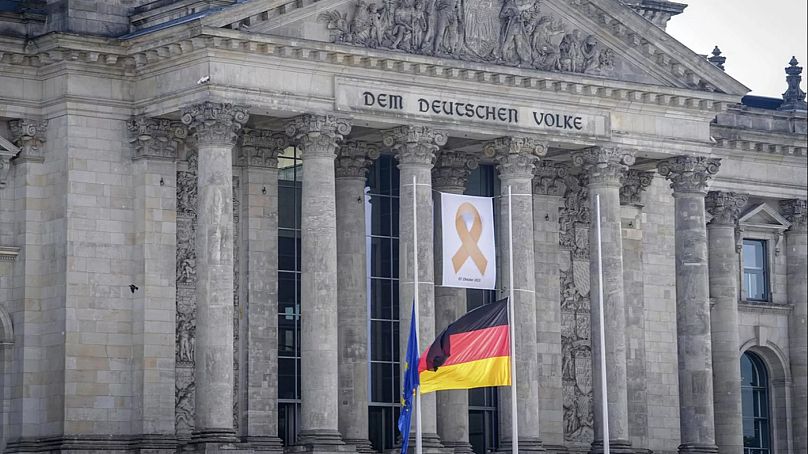Am Reichstagsgebäude hängt am 7. Oktober 2024 ein Gedenkband "7. Oktober 2023" hinter Flaggen auf Halbmast – zum ersten Jahrestag des Hamas-Angriffs.