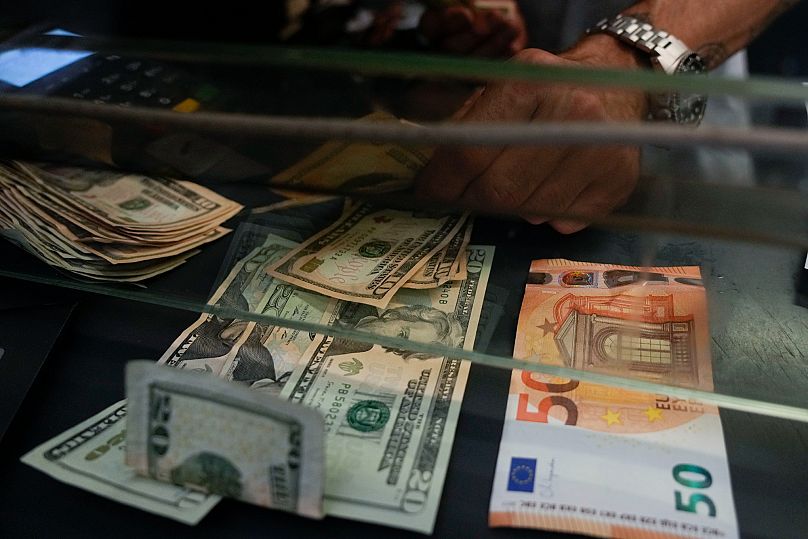 Bir kasiyer, Roma'daki bir döviz bürosunda 50 euroluk banknotu ABD dolarıyla değiştiriyor, 13 Temmuz 2022.