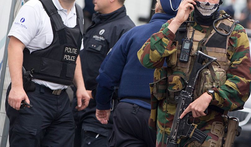 FILE: Belgian police and Belgian Army soldiers stand guard at the scene of a bomb alert on a major shopping street in Brussels on 21 June 2016