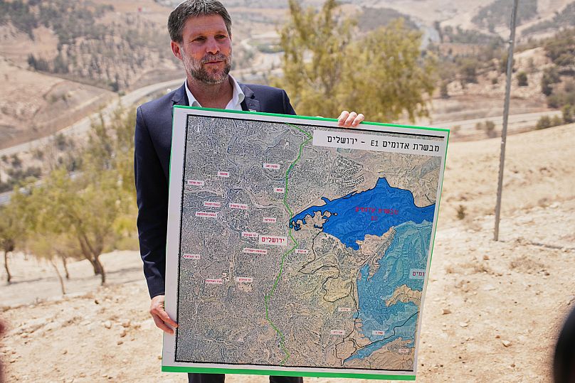Le ministre israélien des finances, Bezalel Smotrich, tient une carte montrant le projet de colonie E1 lors d'une conférence de presse près de la colonie de Maale Adumim, le 14 août 2025.
