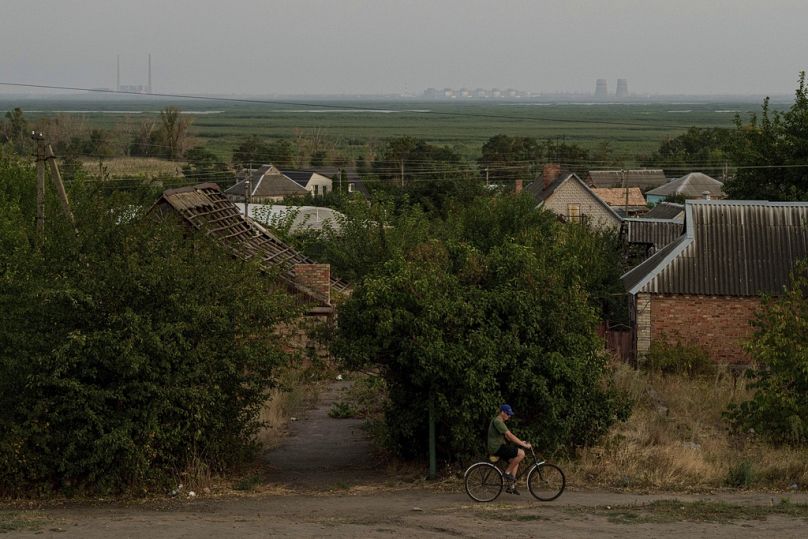 With the Zaporizhzhia nuclear power plant in the background, a bicyclist travels along a path in Nikopol, Ukraine, Sept. 2, 2024. Russian forces have controlled the plant sinc