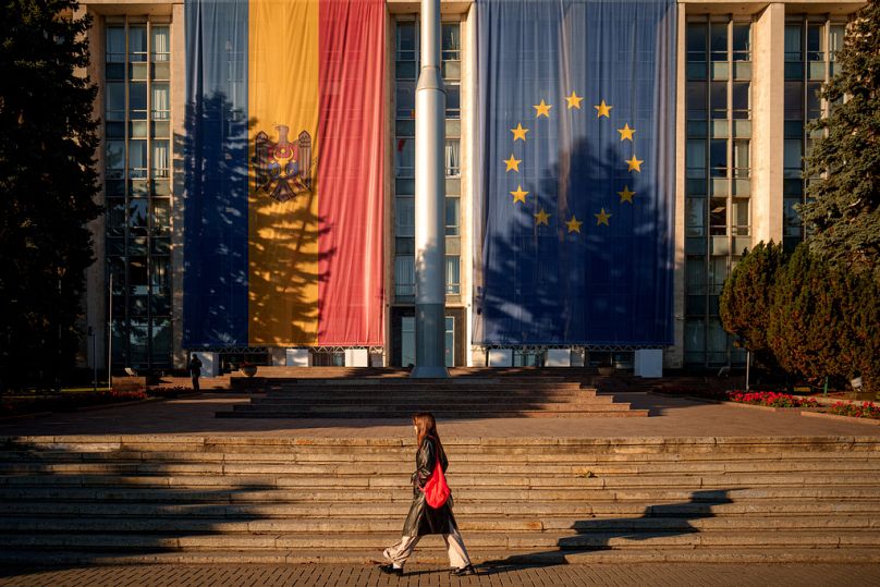 A woman walks in front of the government building, decorated with European Union and Moldovan flags ahead of Sunday's election, Chisinau, Moldova, Friday, Sept. 26, 2025
