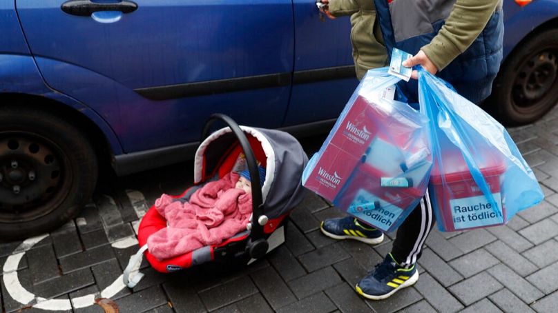 FILE: A French citizen holds packs of cigarettes he bought in Kehl, Germany, at the German-French border Thursday, Oct. 15, 2020
