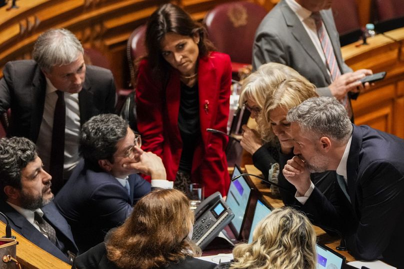 Portuguese Socialist party secretary general Pedro Nuno Santos, foreground and right, speaks with members of the parliament during a break in a debate preceding a vote of conf