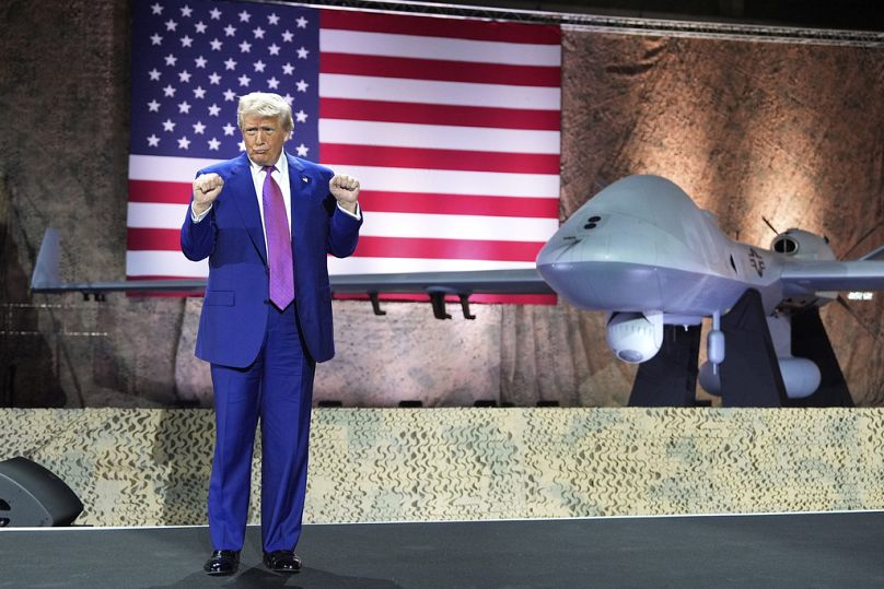الرئيس دونالد ترامب يشير بخلفية طائرة مسيرة من نوع MQ-9 ريبر في قاعدة العُديد الجوية، الخميس 15 مايو 2025، في الدوحة، قطر.