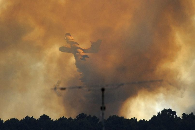 A fire fighting aircraft is almost obscured by smoke and steam as it drops water over a fire outside the village of Pedrogao Grande central Portugal, Monday, June 19, 2017.