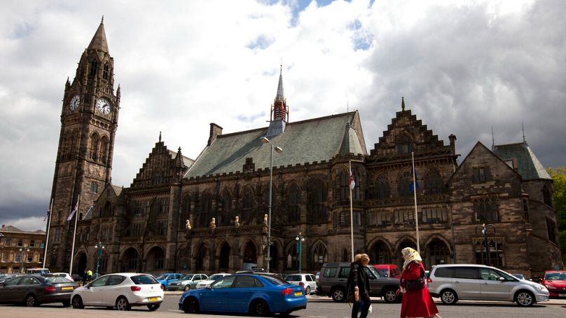 FILE: In this Wednesday, May 16, 2012 photo, pedestrians walk past town hall in Rochdale, England.