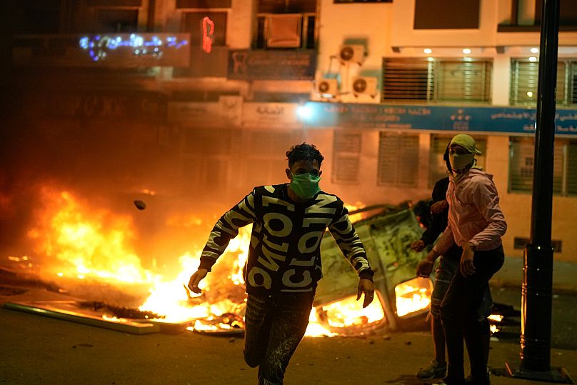 Un jeune marocain passe devant un véhicule de police incendié durant les manifestations à Salé, au Maroc, le mercredi 1er octobre 2025