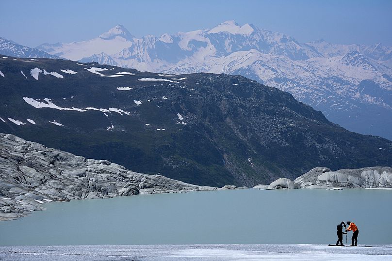 Matthias Huss, of the Federal Institute of Technology in Zurich and glacier monitoring group GLAMOS, and Monica Ursina Jaeger prepare a camera at the Rhone Glacier near Goms.
