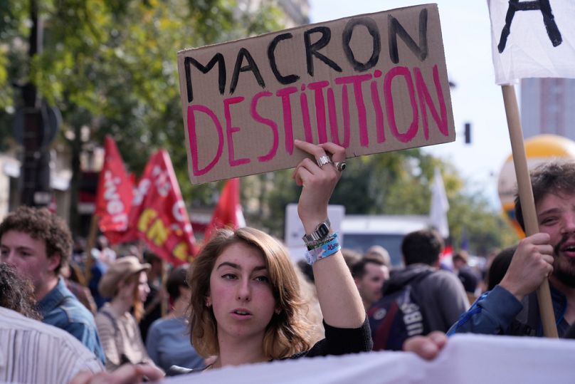 Ένας διαδηλωτής κρατάει μια αφίσα που γράφει "Μακρόν, απόλυση" κατά τη διάρκεια ενός νέου γύρου απεργιών και διαδηλώσεων κατά της υπηρεσιακής κυβέρνησης και της περικοπής δαπανών Πέμπτη, 2 Οκτωβρίου 2025 
