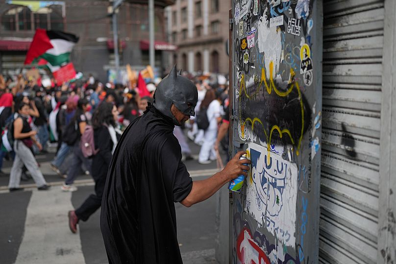 Un joven realiza un grafiti en una protesta combinada propalestina y en conmemoración por una jornada de violencia policial de 1968, conocida como la Matanza de Tlatelolco.