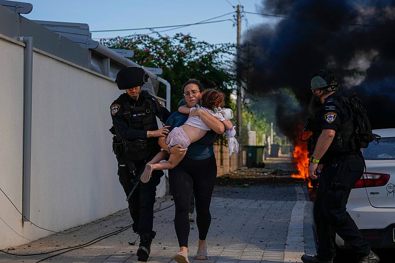 Eine Frau und ein Kind fliehen vor einer vom Hamas abgefeuerten Rakete am 7. Oktober 2023 in Ashkelon