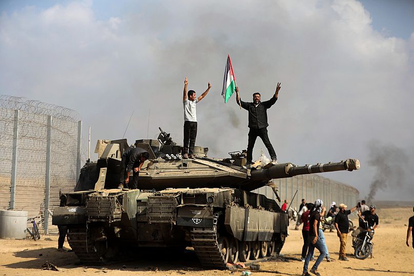Palästinenser tragen ihre Flagge auf einem zerstörten israelischen Panzer an der Grenze zwischen dem Gazastreifen und Israel
