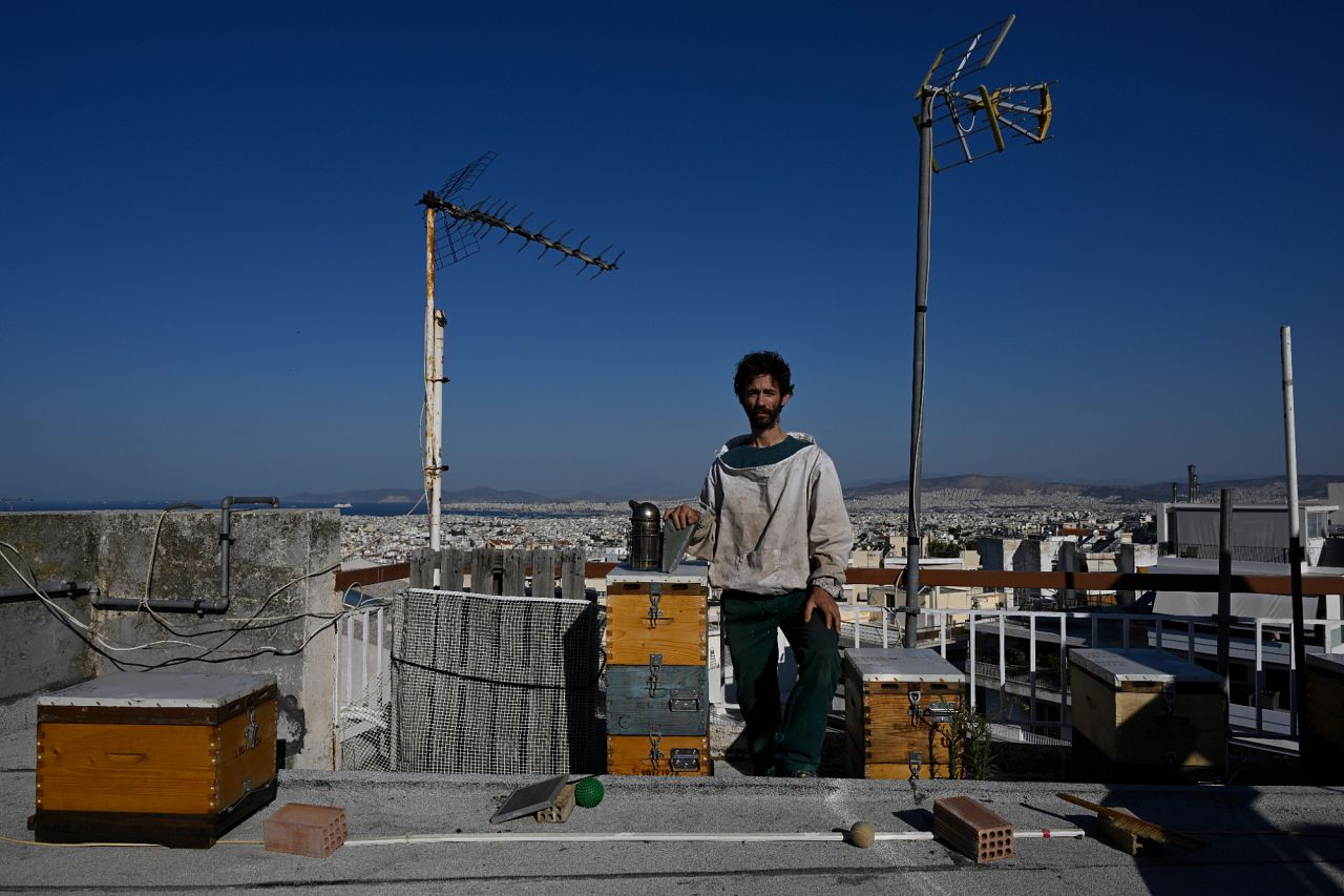 Nikos Chadjilias poses among his urban apiary on the roof of a building in the Ilioupoli suburb of Athens, Greece.