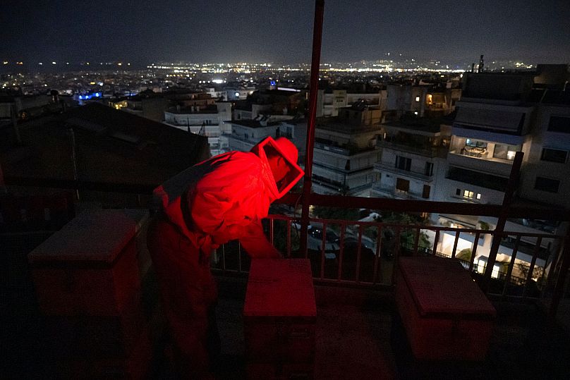Konstantinos Pantoudis inspects a beehive after a late-night transfer on the rooftop of a building in the Ilioupoli suburb of Athens, Greece.