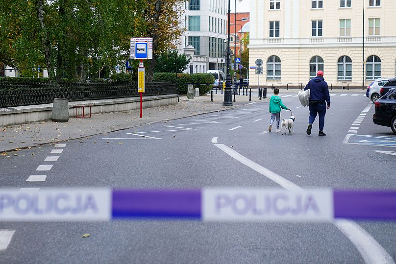 Pedestrians walk behind police tape in Warsaw, 14 October, 2023