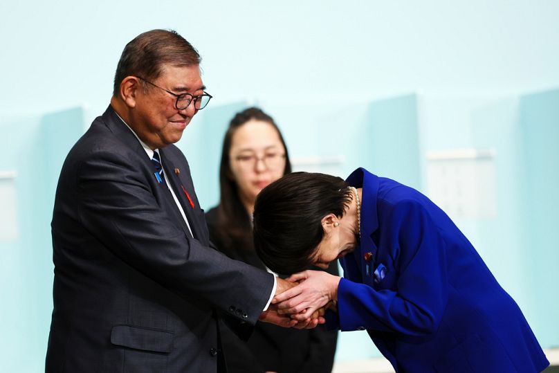 Newly-elected leader of Japan's Liberal Democratic Party (LDP) Sanae Takaichi, right, bows as she shakes hands with Prime Minister Shigeru Ishiba after winning the LDP leaders