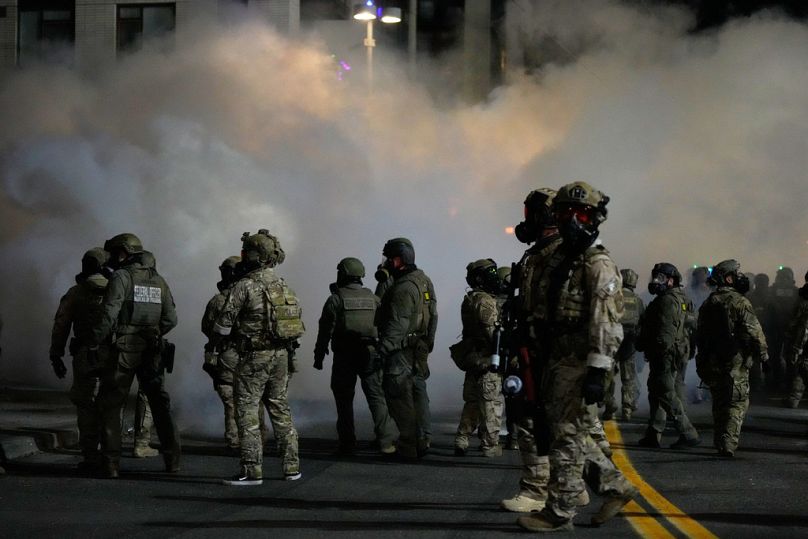Law enforcement officers stand in tear gas outside a U.S. Immigration and Customs Enforcement facility during a protest on Saturday, Oct. 4, 2025, in Portland, Ore. (AP Photo/