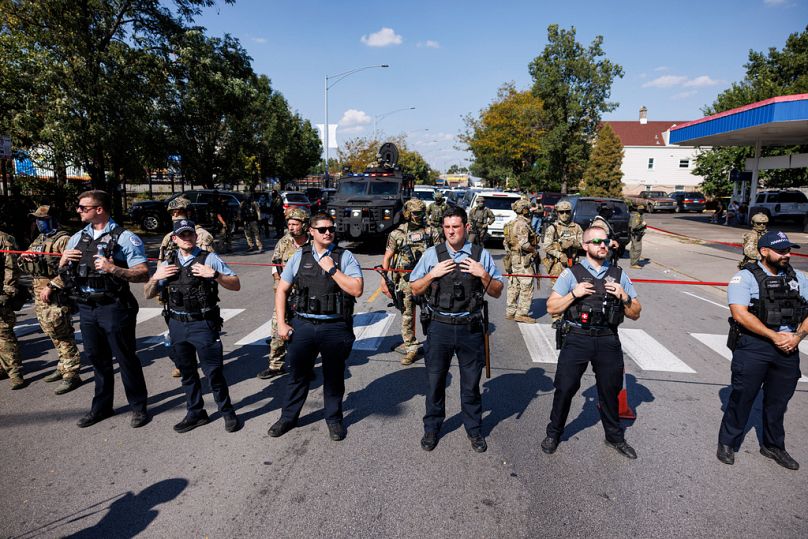 Polizisten des Chicago Police Department (CPD) stehen am Samstag, dem 4. Oktober 2025, im Stadtteil Brighton Park in Chicago vor Bundesbeamten.
