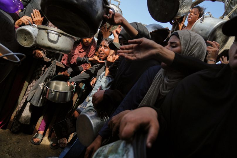 Palestinians struggle to get donated food at a community kitchen in Khan Younis, southern Gaza Strip, Sunday, Oct. 5, 2025
