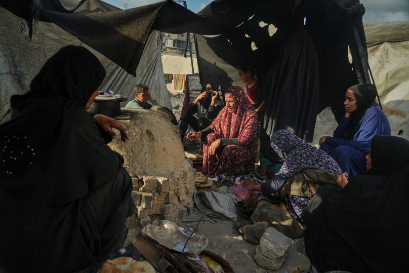 Palestinian women bake bread in a clay oven, using plastic for fire, at a UN school used as a shelter for displaced Palestinians in Khan Younis, Sunday, Oct. 5, 2025