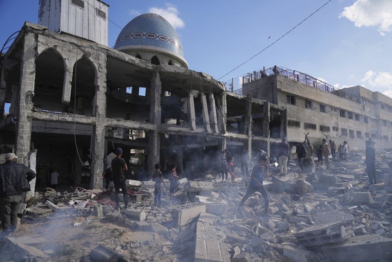 فلسطينيون يتفقدون أنقاض مسجد الأنصار بعد غارة إسرائيلية في دير البلح وسط غزة، الاثنين 2 يونيو 2025.