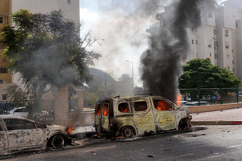 Cars are on fire after they were hit by rockets from the Gaza Strip in Ashkelon, 7 October, 2023