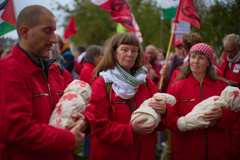 Protesters mimick holding the bodies of children demanding their government do more to halt Israel's war on Gaza, during a protest in Amsterdam, Netherlands, Oct. 5, 2025