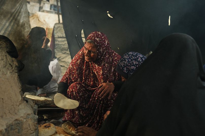 نساء فلسطينيات يخبزن في فرن فخاري باستخدام البلاستيك كوقود في مدرسة أممية ملجأ للنازحين في خان يونس.