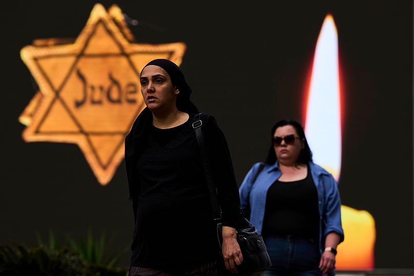 People walk next to a billboard that reads "Jude," Jew in German, resembling the one Jews were forced to wear in Nazi Germany, in Ramat Gan, 24 April, 2025