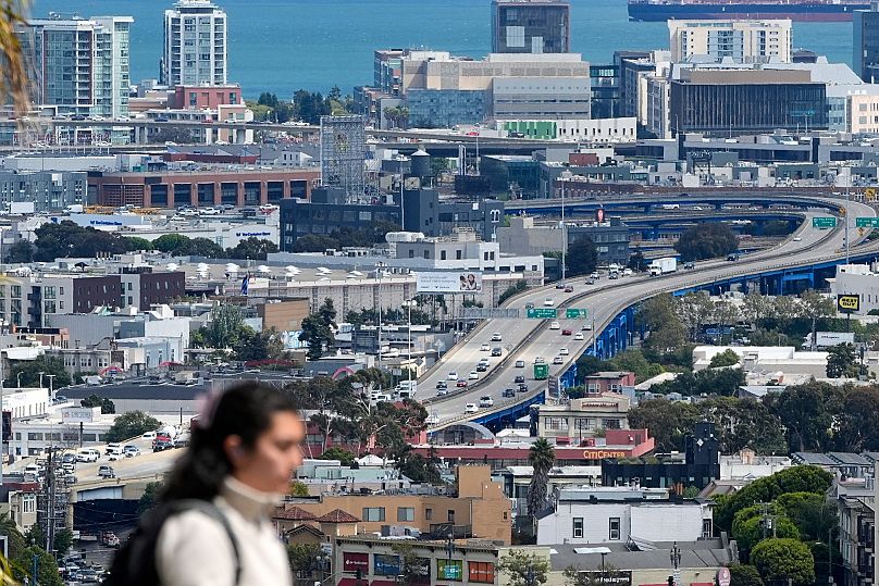 A pedestrian crosses the street in front of a freeway the bay in San Francisco, 4 September, 2025