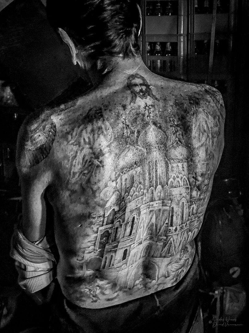 A man shows his back tattoos, as part of the exhibition 'Surrounded by Criminals'