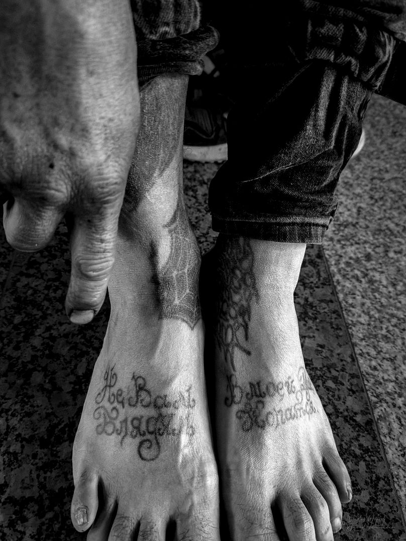 A man shows tattoos on his feet, as part of the 'Surrounded by Criminals' exhibition 