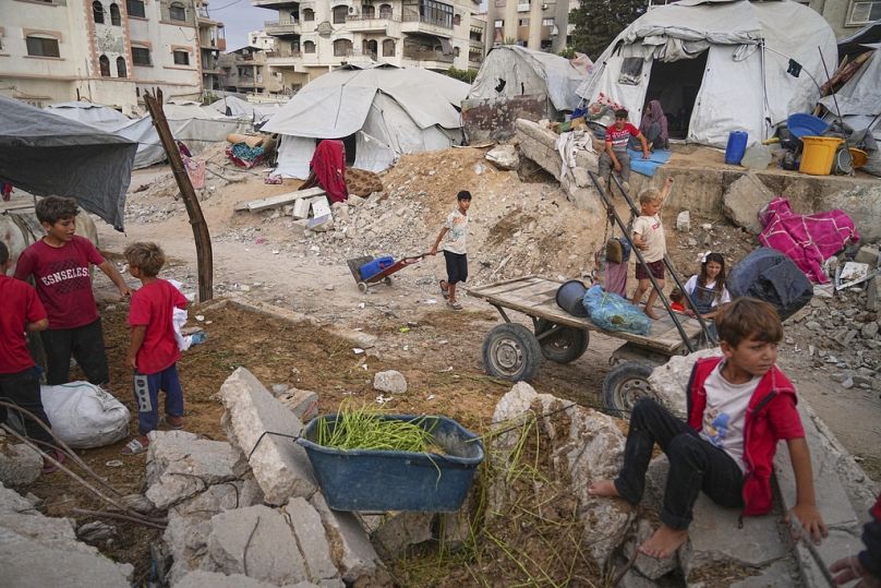 أطفال فلسطينيون في مخيم أقيم وسط البنية التحتية المتضررة من الحرب في مدينة غزة، الاثنين 23 يونيو 2025.